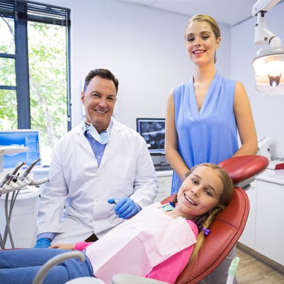 Dentist with smiling patient and mother